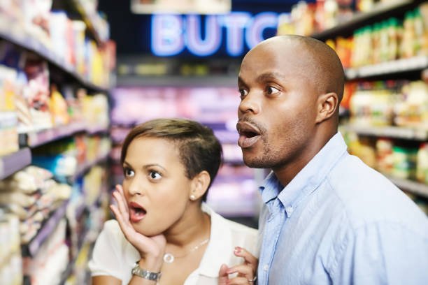 Inflation is out of control! Couple react with dismay as they see the price of items on a supermarket shelf.