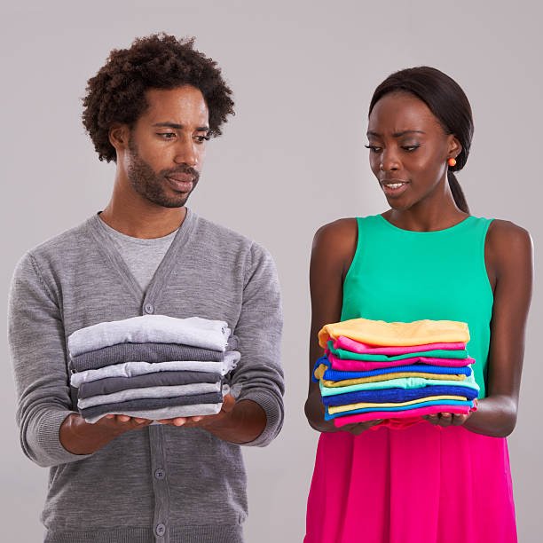 Young man and woman each holding a neatly folded pile of clothes