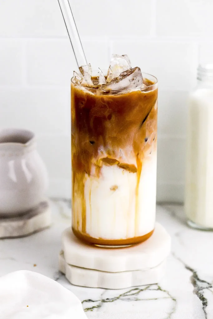 Layered iced caramel macchiato with espresso swirling into milk over ice