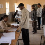 Polling assistants verifying voters and applying indelible ink at a polling station in Zambia