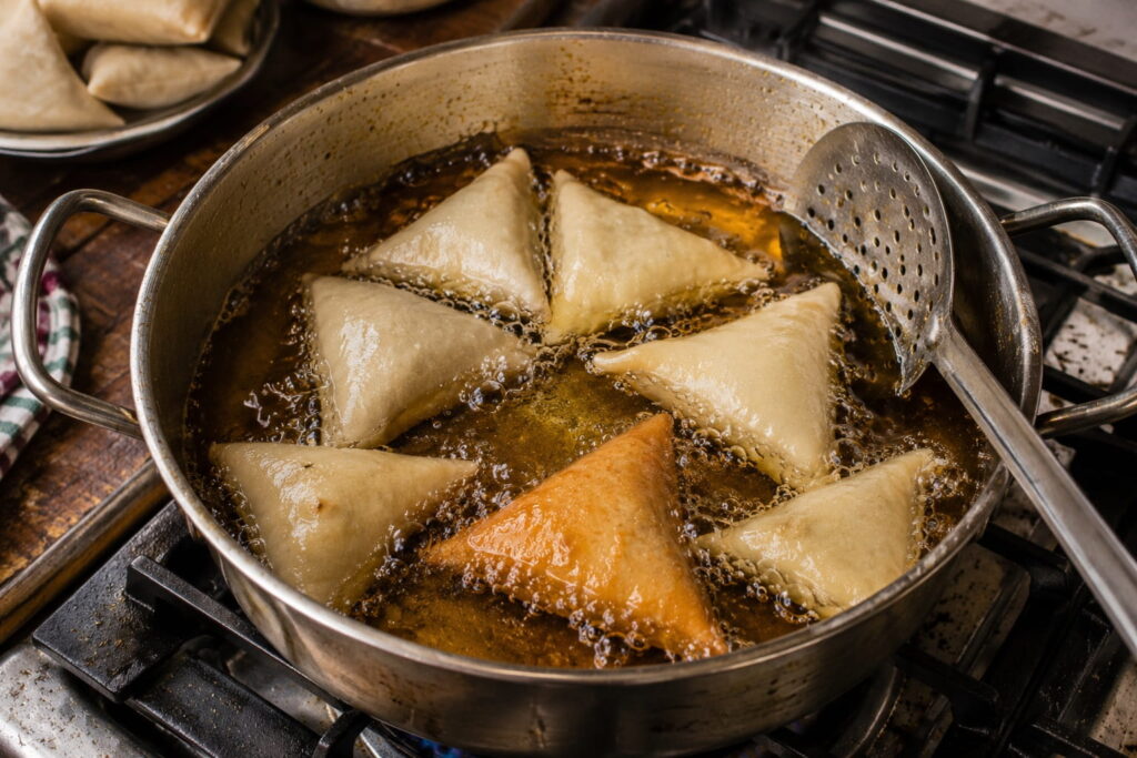 Zambian samosas frying in hot oil until golden brown