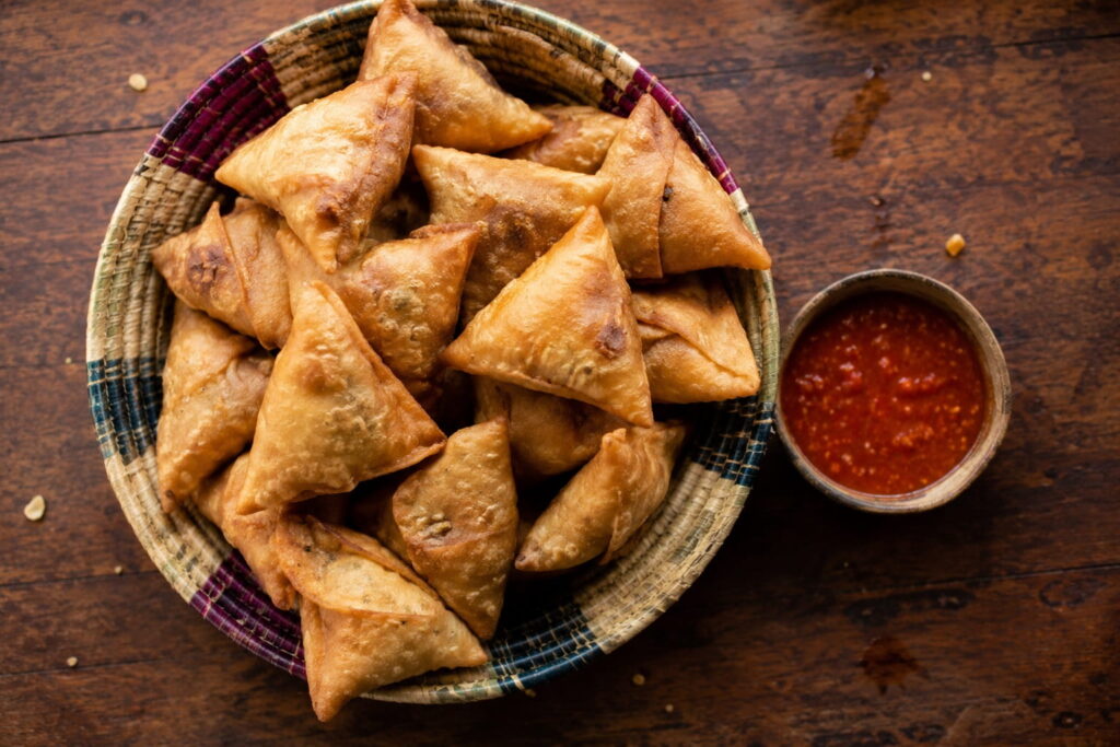 Basket of golden fried Zambian samosas served with chilli sauce