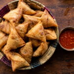 How to Make Samosas in Zambia (Authentic Zambian Samoosa Recipe) Basket of golden fried Zambian samosas served with chilli sauce