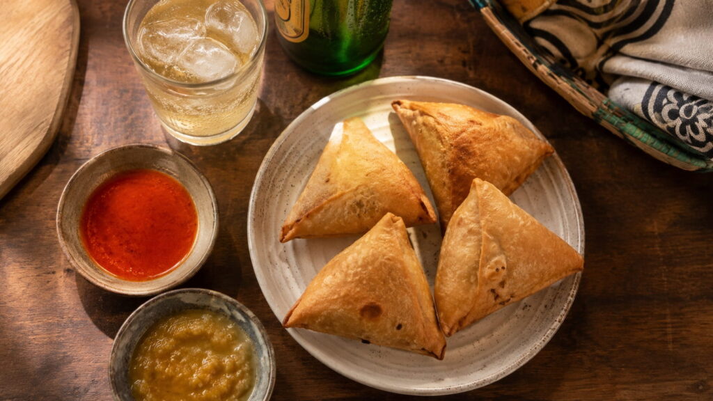 Plate of Zambian samosas served with chilli sauce and mango chutney