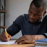 Zambian Application Letter as a General Worker (With Free Samples) Man writing a Zambian application letter as a general worker at a desk